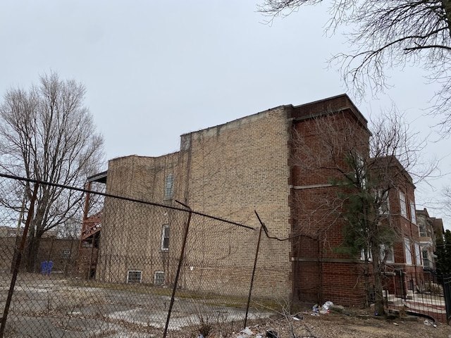 view of side of property with fence and brick siding