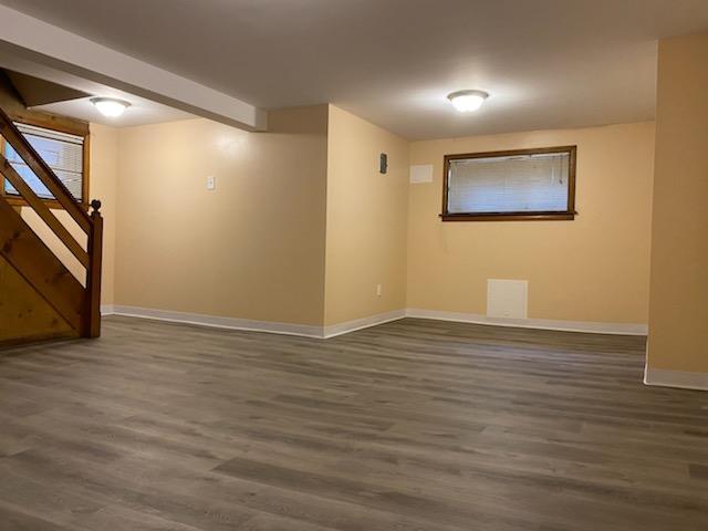 finished basement featuring visible vents, baseboards, wood finished floors, and stairway