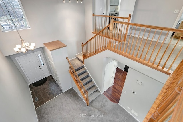 stairway with carpet floors, a towering ceiling, baseboards, and an inviting chandelier