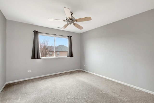 carpeted spare room with ceiling fan and baseboards