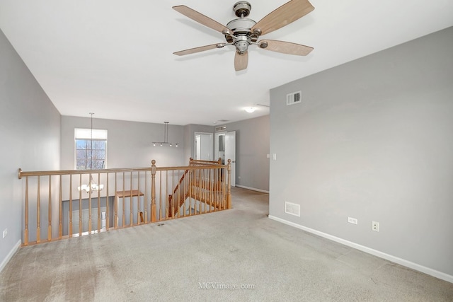 carpeted spare room featuring baseboards, visible vents, and a notable chandelier