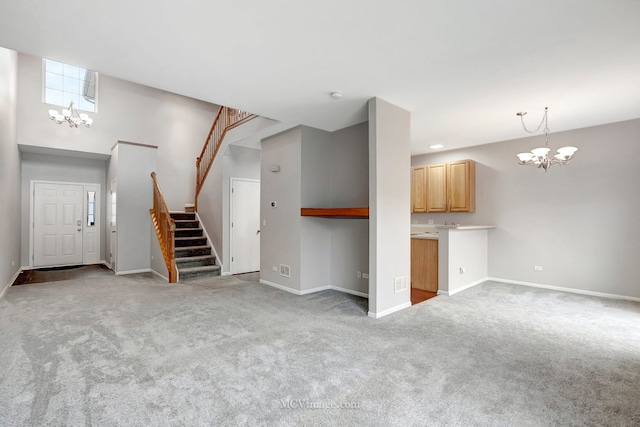 unfurnished living room featuring a chandelier, carpet, baseboards, and stairs