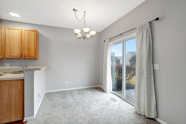 unfurnished dining area with baseboards, carpet, visible vents, and a sink