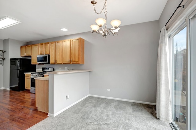 kitchen with pendant lighting, stainless steel appliances, light countertops, a peninsula, and baseboards