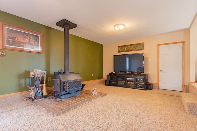 carpeted living area with a wood stove and baseboards