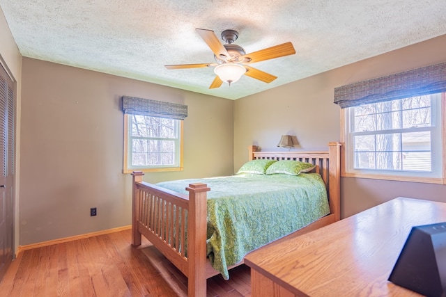 bedroom with a closet, baseboards, a textured ceiling, and wood finished floors