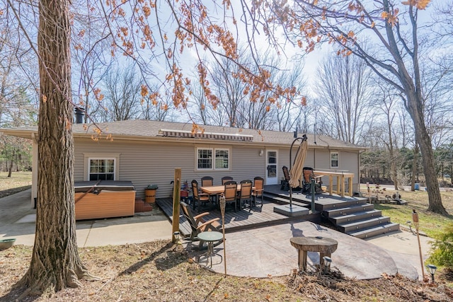 rear view of property with a wooden deck, a patio area, and a hot tub