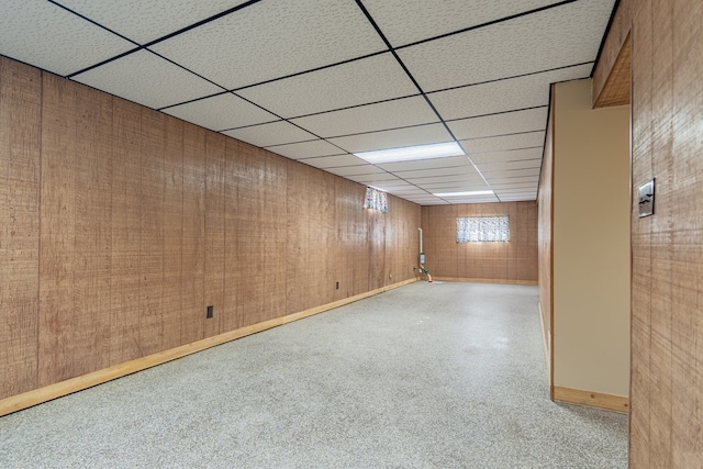 finished basement featuring a drop ceiling and baseboards