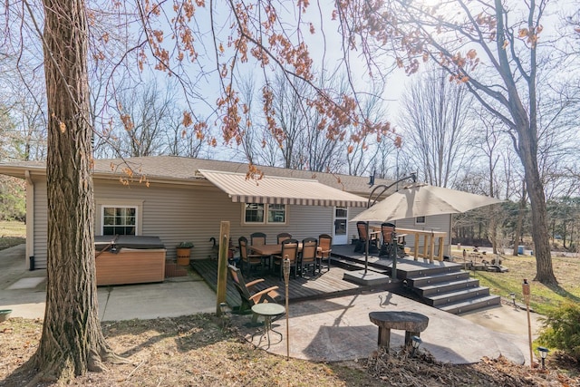 rear view of property featuring a deck, outdoor dining space, and a hot tub