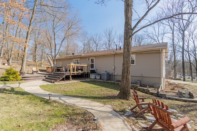 rear view of house with a deck, cooling unit, and a yard