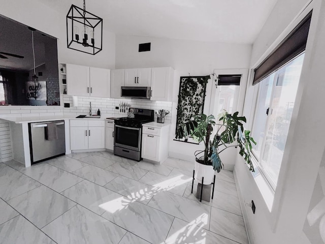 kitchen with marble finish floor, tasteful backsplash, appliances with stainless steel finishes, white cabinets, and a sink