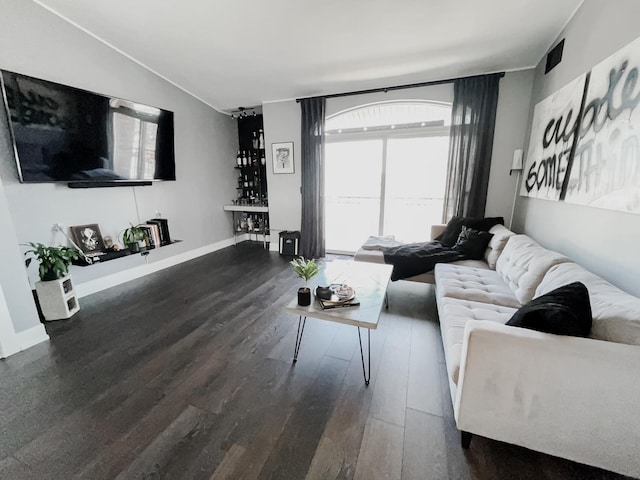 living room featuring lofted ceiling, baseboards, and wood finished floors