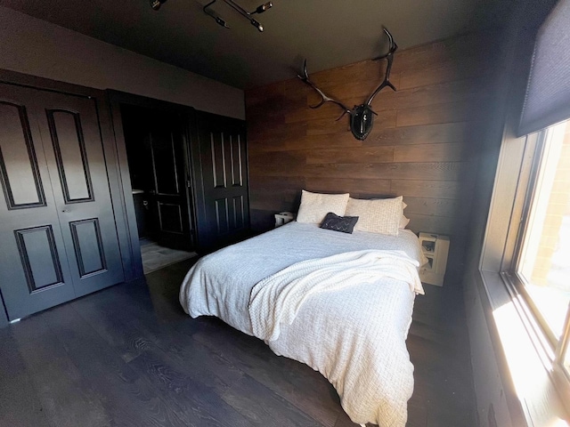 bedroom with dark wood-style floors and wooden walls