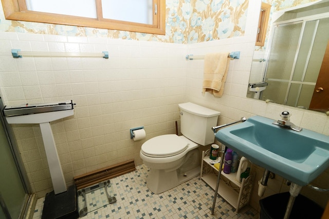 full bath featuring wallpapered walls, toilet, wainscoting, a stall shower, and a sink