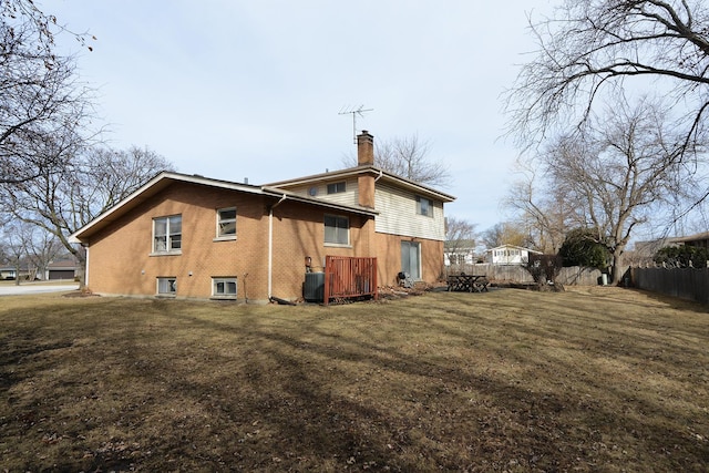 rear view of property featuring a yard, fence, central AC, and a chimney