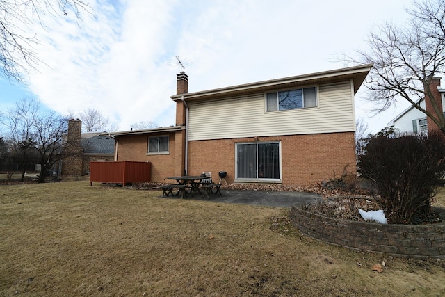 back of house with brick siding, a patio area, a chimney, and a yard