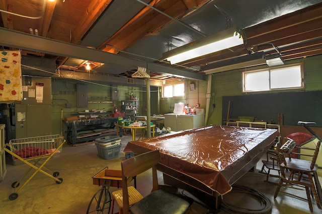 interior space featuring electric panel, unfinished concrete flooring, concrete block wall, pool table, and washing machine and clothes dryer