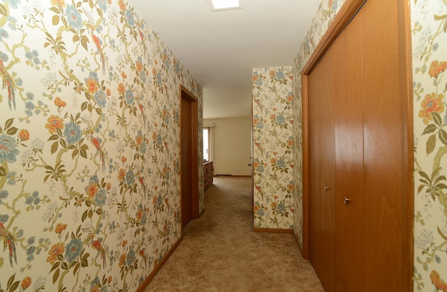 hall featuring baseboards, light colored carpet, and wallpapered walls