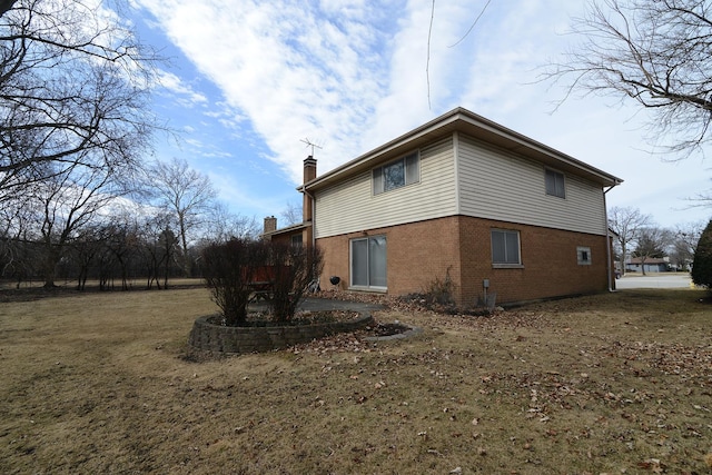 view of home's exterior featuring brick siding and a chimney