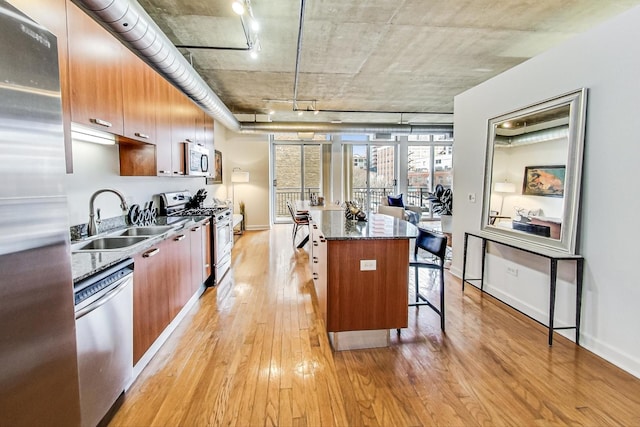 kitchen with light wood-type flooring, a kitchen bar, a sink, a kitchen island, and stainless steel appliances