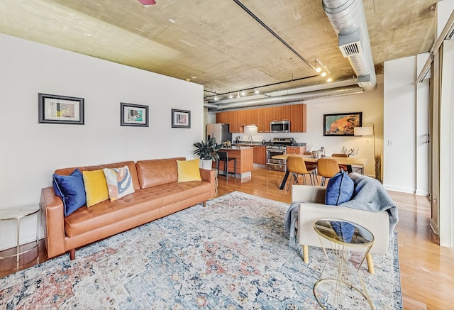 living room featuring visible vents, baseboards, and light wood-style floors