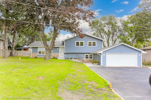 tri-level home featuring entry steps, an attached garage, fence, driveway, and a front lawn