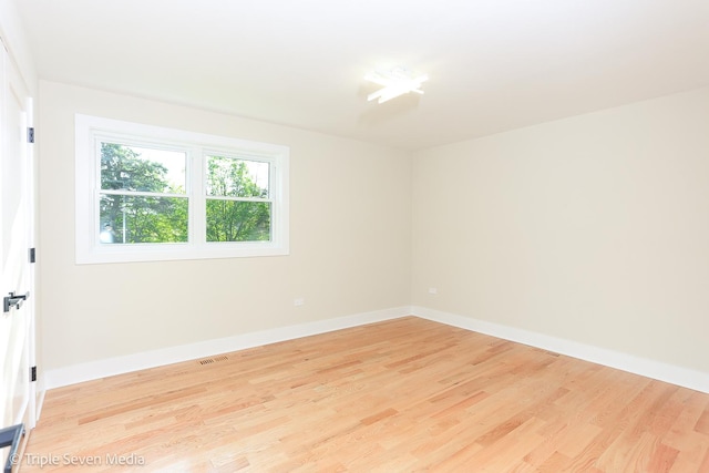 unfurnished room with visible vents, light wood-style flooring, and baseboards