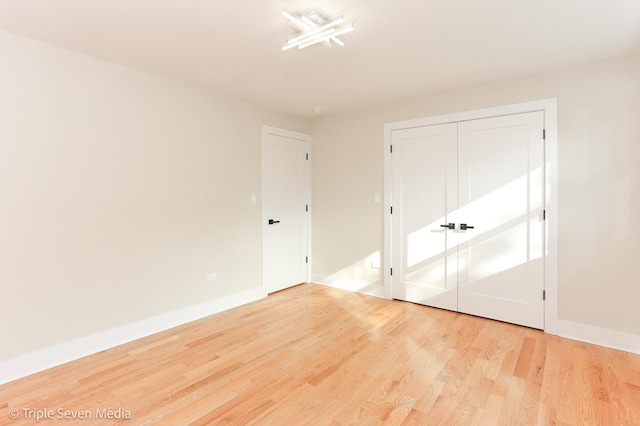 unfurnished bedroom featuring a closet, light wood-style flooring, and baseboards