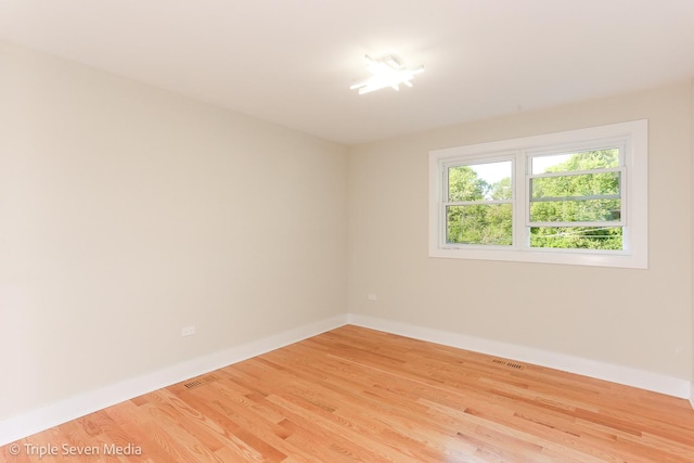 unfurnished room with light wood-type flooring, visible vents, and baseboards