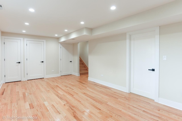 finished below grade area featuring stairs, light wood finished floors, baseboards, and recessed lighting