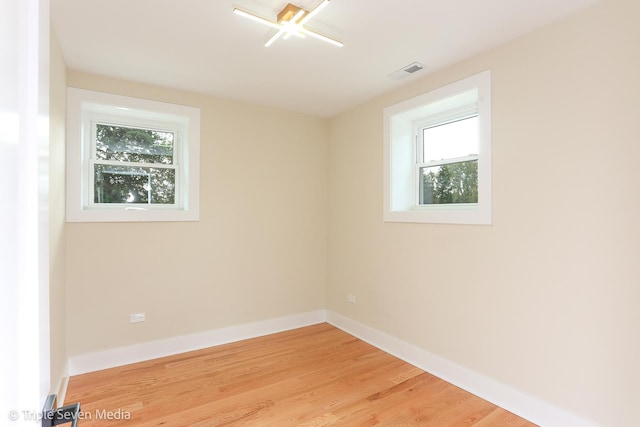 unfurnished room with light wood finished floors, baseboards, and visible vents