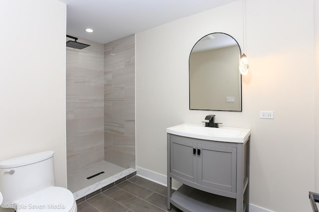 full bath with toilet, recessed lighting, vanity, baseboards, and a tile shower