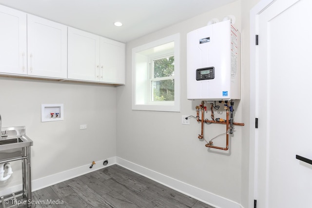 laundry area with dark wood-style flooring, water heater, cabinet space, gas dryer hookup, and baseboards