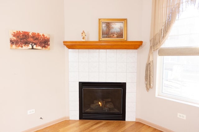 details with baseboards, wood finished floors, and a tile fireplace