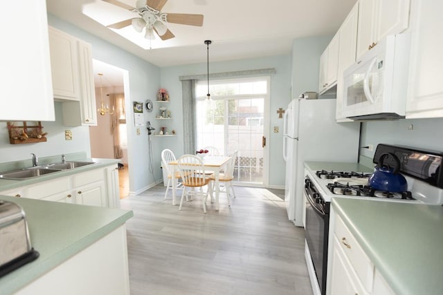 kitchen with gas range, white microwave, light wood-type flooring, white cabinetry, and a sink