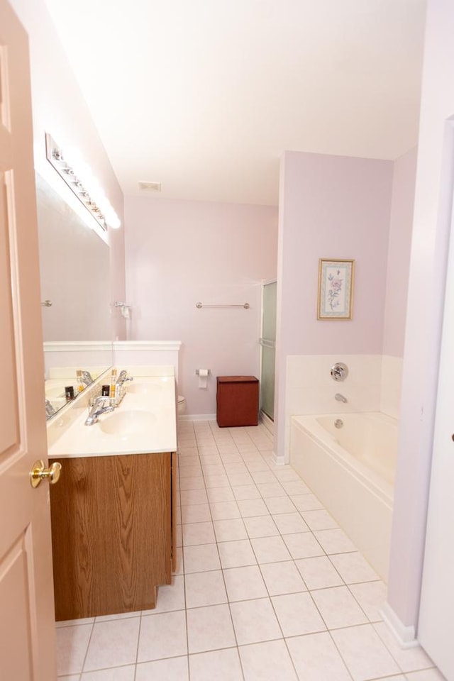 bathroom with tile patterned flooring, a garden tub, vanity, and toilet