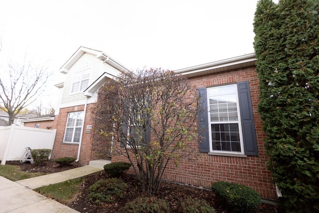 view of home's exterior with brick siding and fence