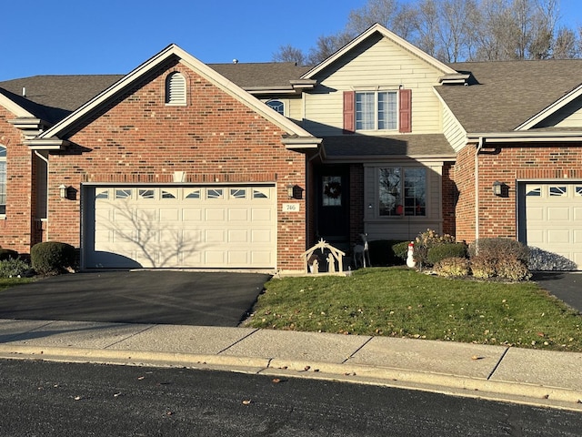 traditional-style house featuring aphalt driveway, a front yard, brick siding, and an attached garage