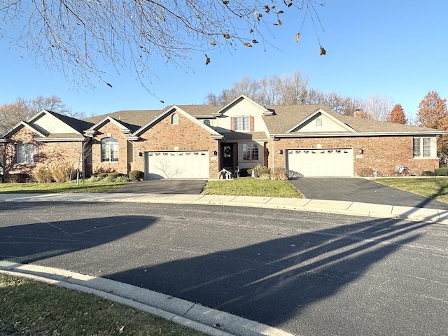 traditional-style house with driveway, a garage, a front lawn, and brick siding