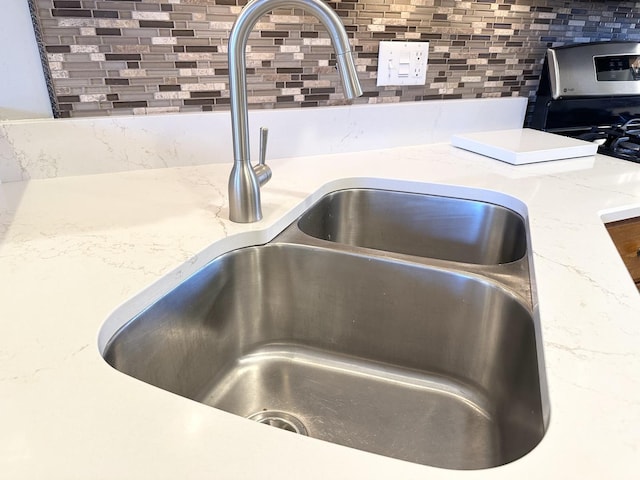 interior details with a sink and decorative backsplash