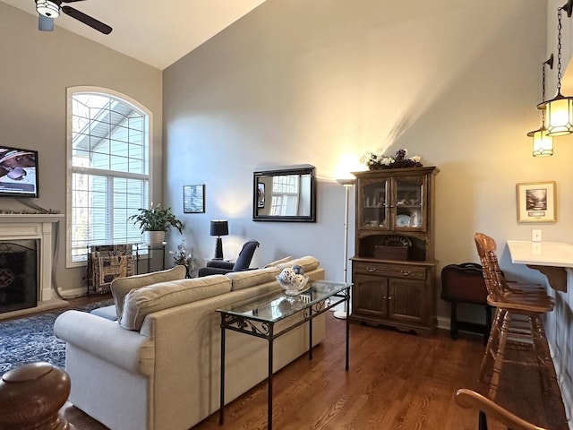 living area featuring high vaulted ceiling, plenty of natural light, dark wood-style floors, and ceiling fan