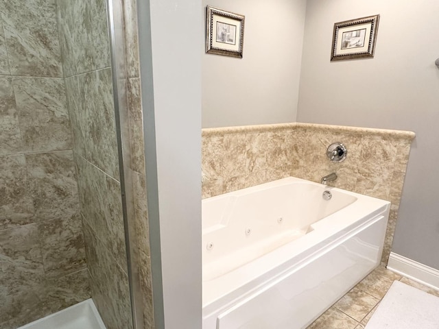 full bath featuring a whirlpool tub, baseboards, and a tile shower