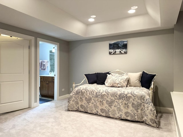 bedroom featuring a raised ceiling, ensuite bathroom, baseboards, and carpet floors