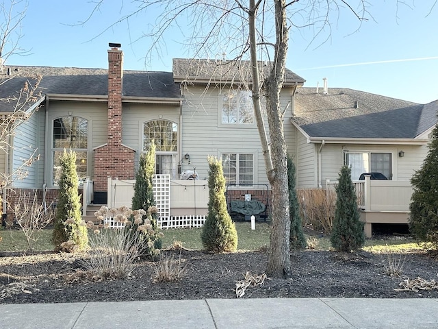 exterior space with roof with shingles and a chimney