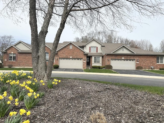 traditional home featuring brick siding, an attached garage, a shingled roof, and driveway