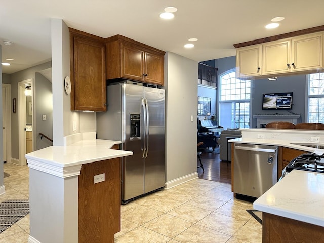 kitchen with a peninsula, appliances with stainless steel finishes, light countertops, and recessed lighting