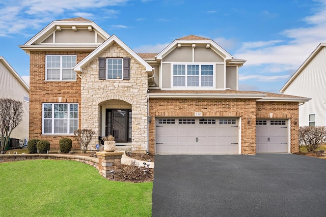 craftsman house featuring a front lawn, brick siding, stone siding, and driveway