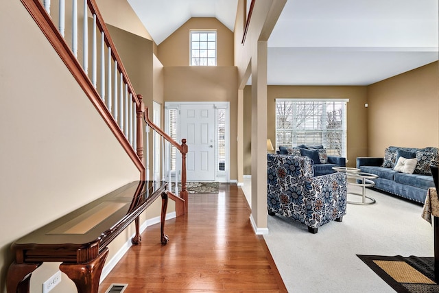 entrance foyer with baseboards, high vaulted ceiling, wood finished floors, and stairs