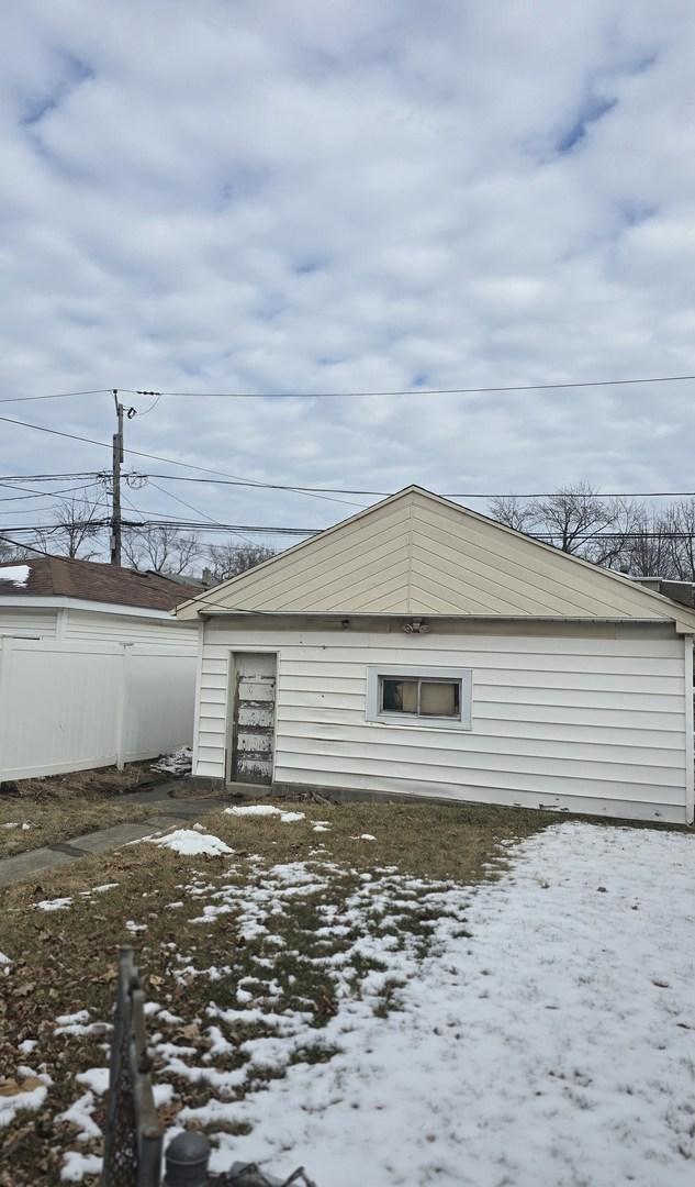 snow covered garage featuring fence