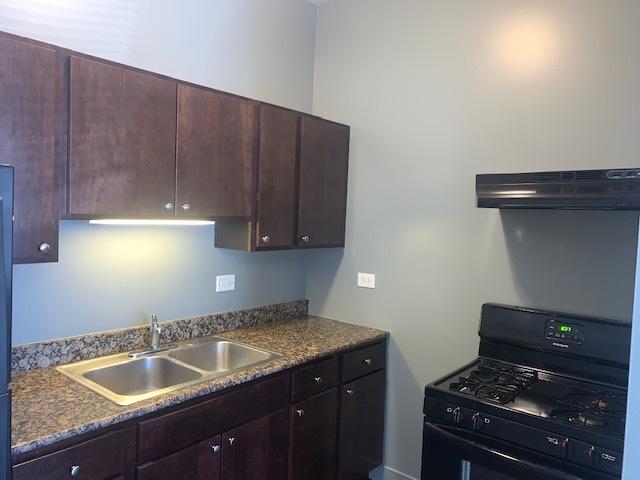 kitchen with under cabinet range hood, a sink, black gas range, and dark brown cabinetry